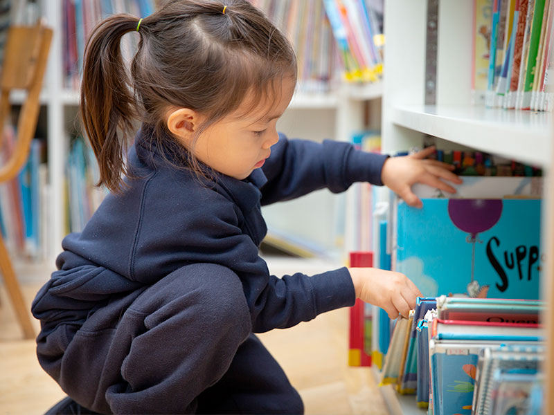 Child choosing a book from the book shelf