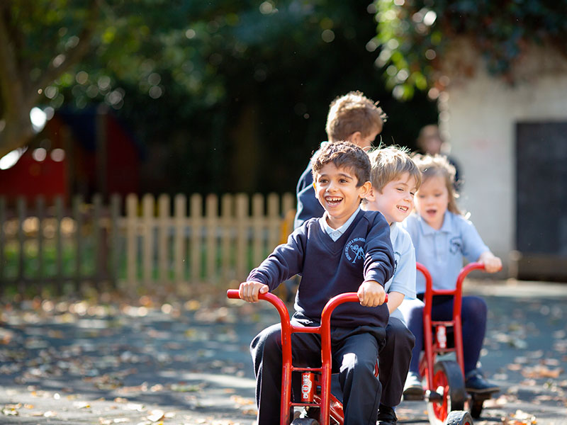 Children riding tricycles and bicycles outside