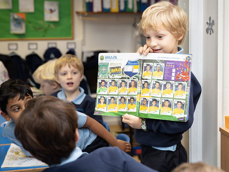 Boy showing football collection to class